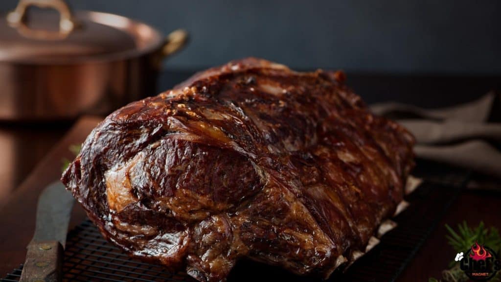 Cooked prime rib roast on metal rack with knife 